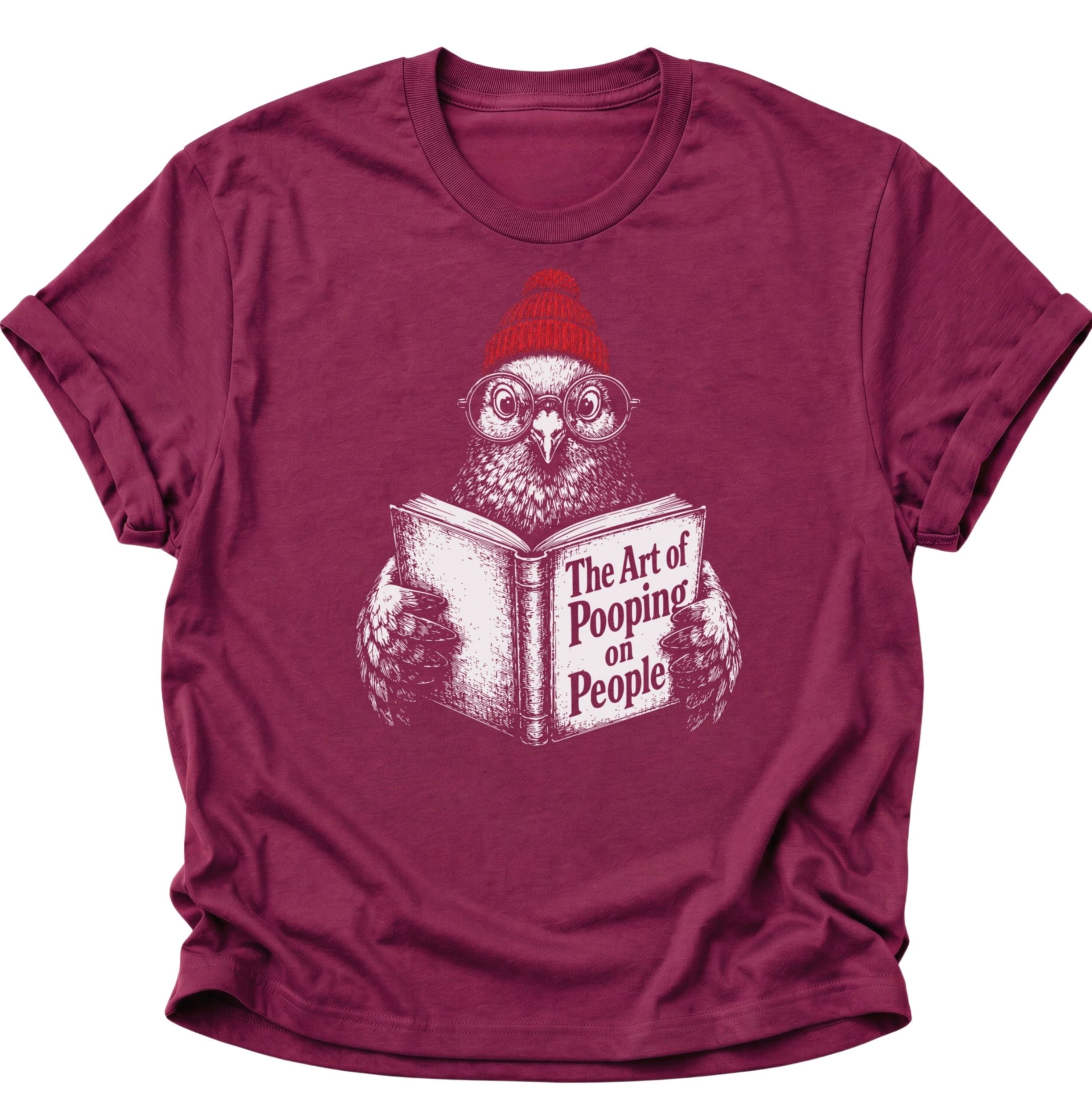 Cardinal red Unisex T-Shirt mit Vogel, Bommelmütze und dem Buch „The Art of Pooping on People“ von Pine & River.
