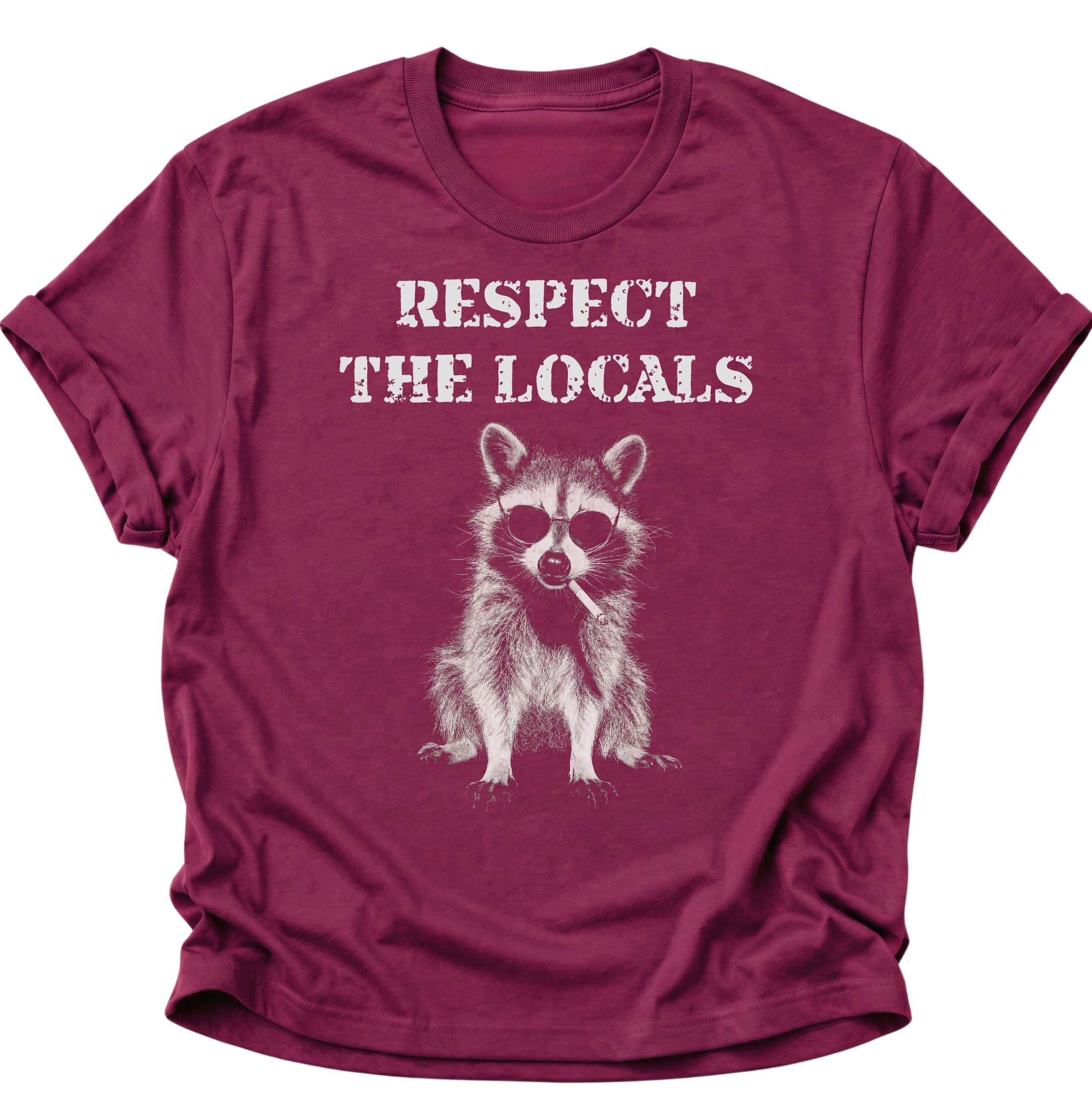 Cardinal red Unisex T-Shirt mit Waschbär, Sonnenbrille und großem „RESPECT THE LOCALS“-Schriftzug von Pine & River.
