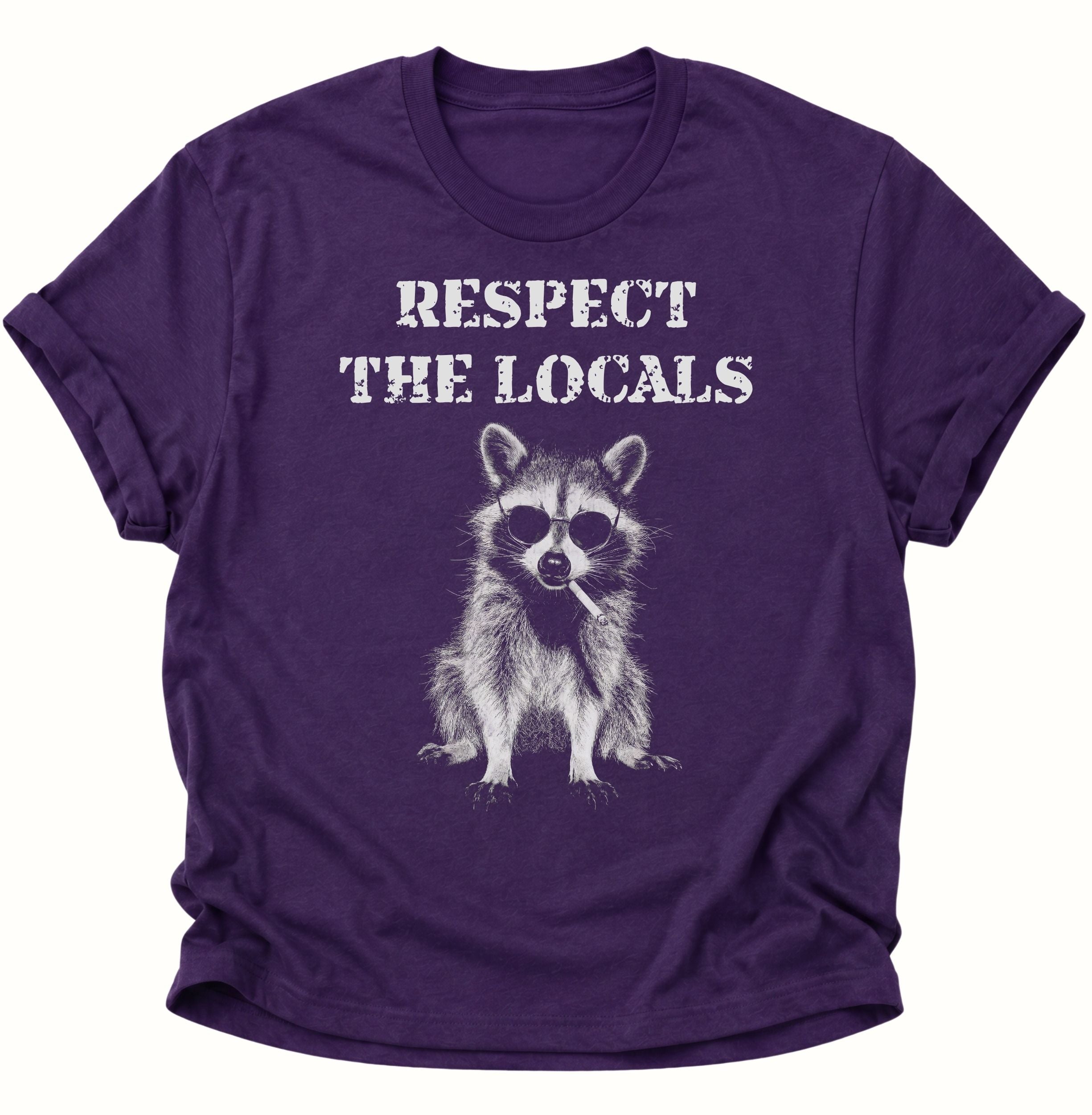 Purple Unisex T-Shirt mit Waschbär, dunkler Sonnenbrille und „RESPECT THE LOCALS“ von Pine & River.
