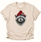 Naturfarbenes FCK NZS T-Shirt mit realistisch gezeichnetem Waschbär und roter Bommelmütze
